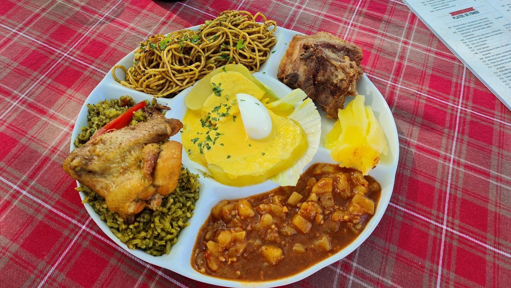 A plate of food with various dishes including fried chicken, rice, and a side of beans.