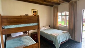 A room with two bunk beds, a ceiling fan, a window with curtains, and a small bedside table. - HOSPEDAJE EL CASCABEL (Sunampe)