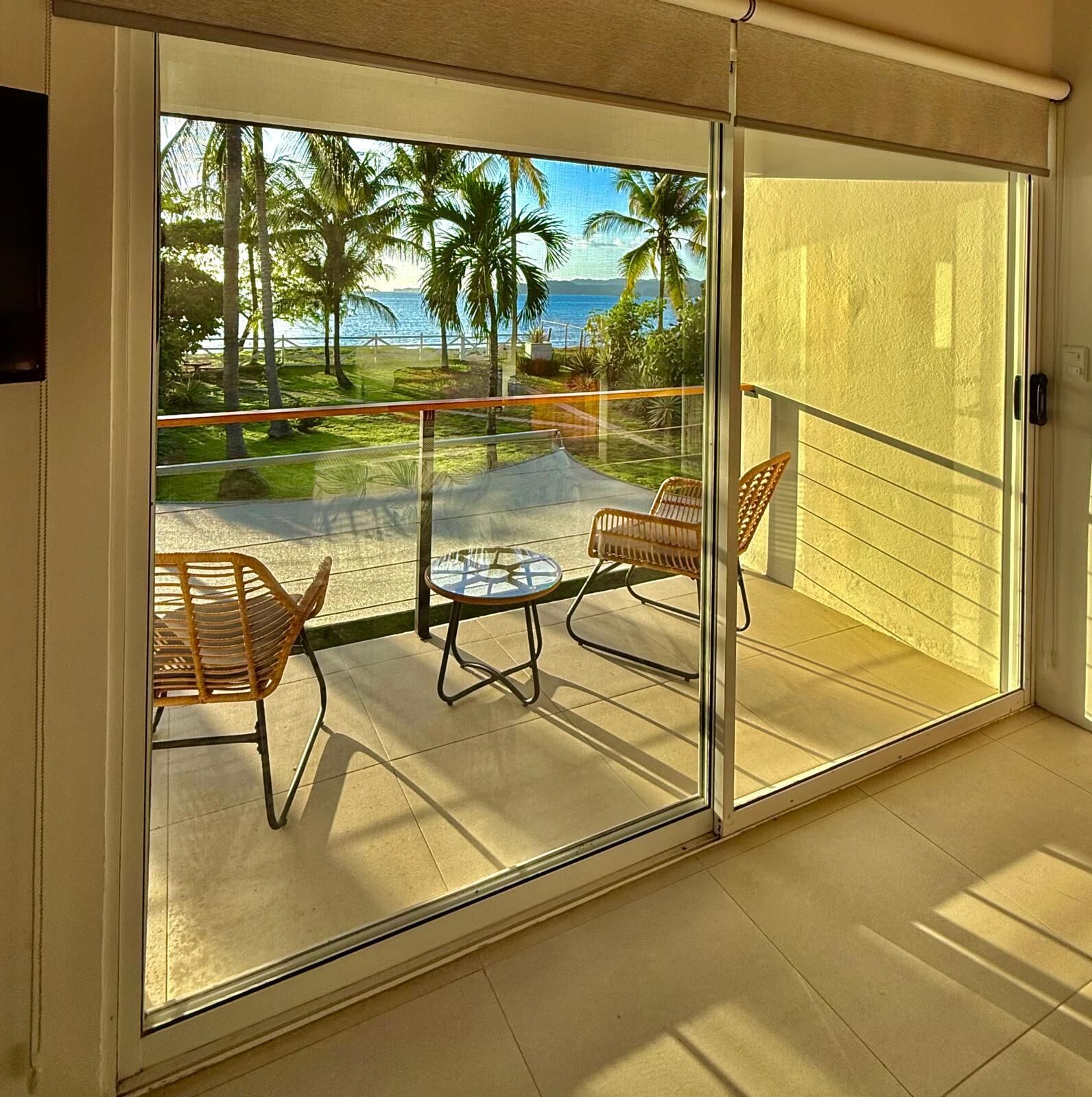 A balcony with a glass door, two wicker chairs, and a small table.