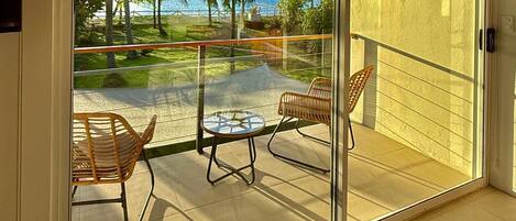 A balcony with a glass door, two wicker chairs, and a small table.
