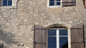 A stone building with a large arched window and wooden shutters.