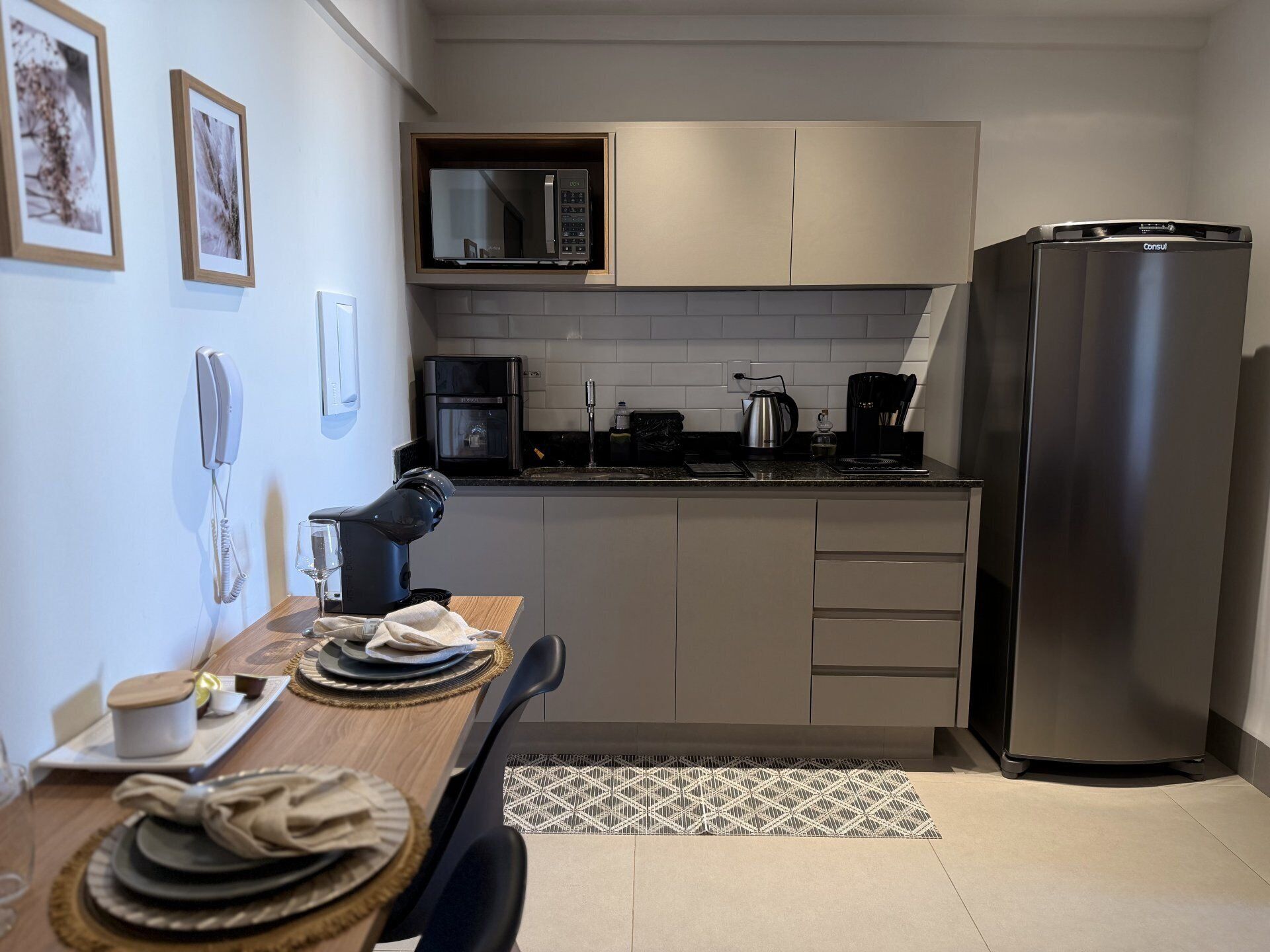 A compact kitchen with a built-in microwave, a coffee maker, and a refrigerator.