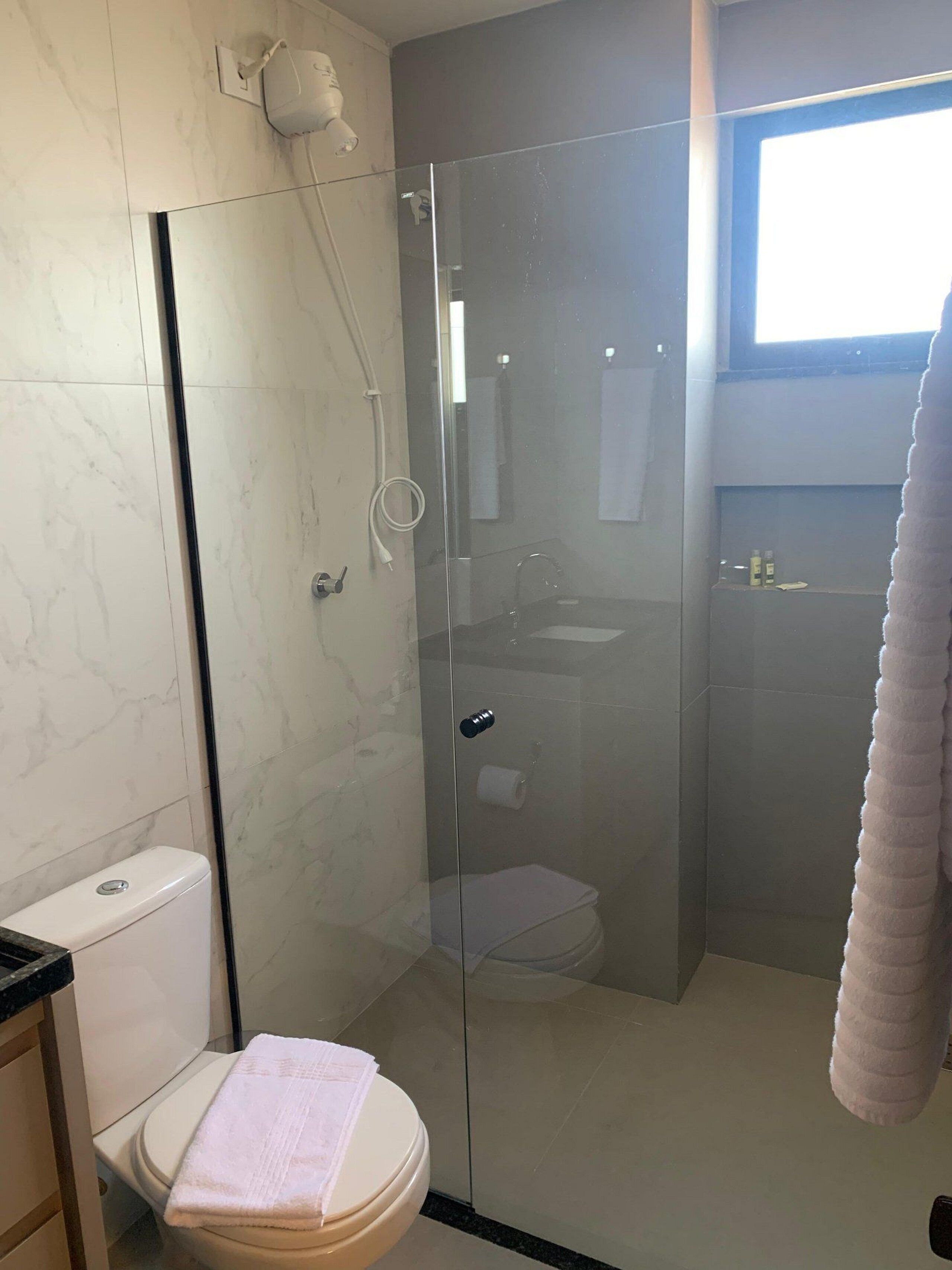 Un baño con ducha de vidrio, inodoro y lavamanos.