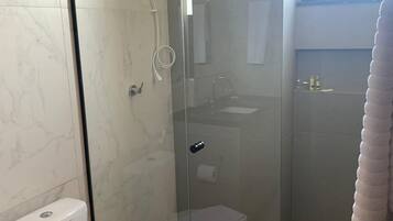 A bathroom with a glass-enclosed shower, a toilet, and a sink.
