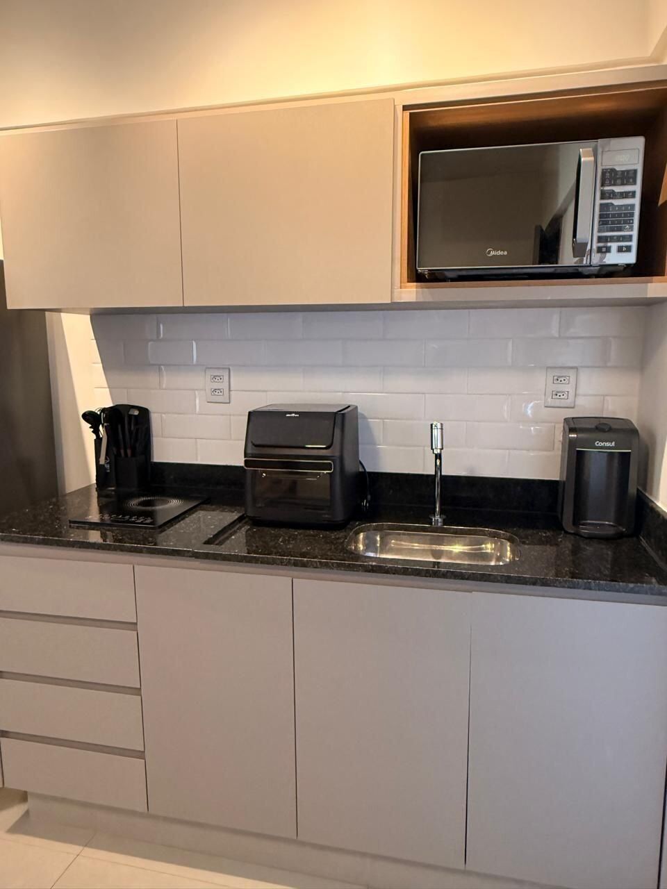 A modern kitchen with a microwave, toaster, and coffee maker on the countertop.