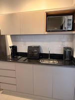 Una cocina moderna con microondas, tostadora y cafetera sobre la encimera.