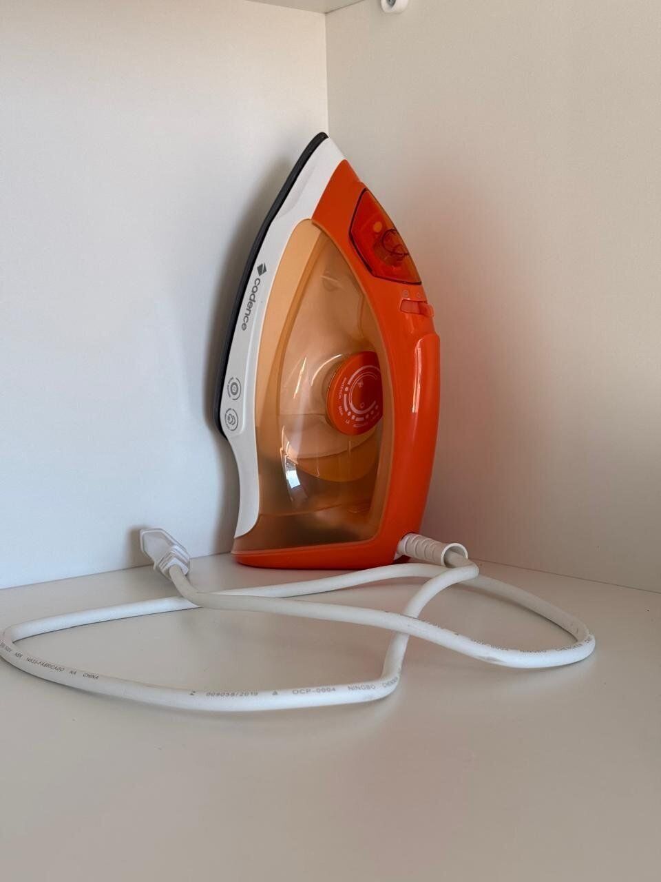 An iron with a cord plugged into a power outlet.