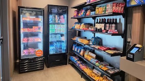 Een automaat met drankjes, zowel gekoeld als niet-gekoeld, planken vol snacks en een betaalterminal.