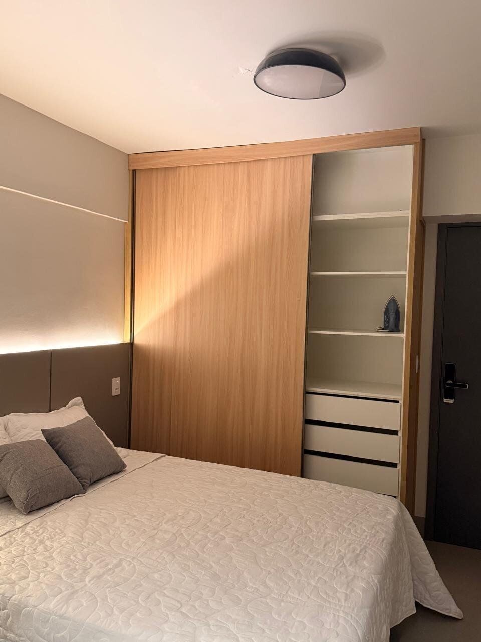 Un dormitorio con cama, armario con espejo y puerta.