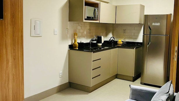 A modern kitchen with a built-in microwave, a stainless steel refrigerator, and a black countertop.