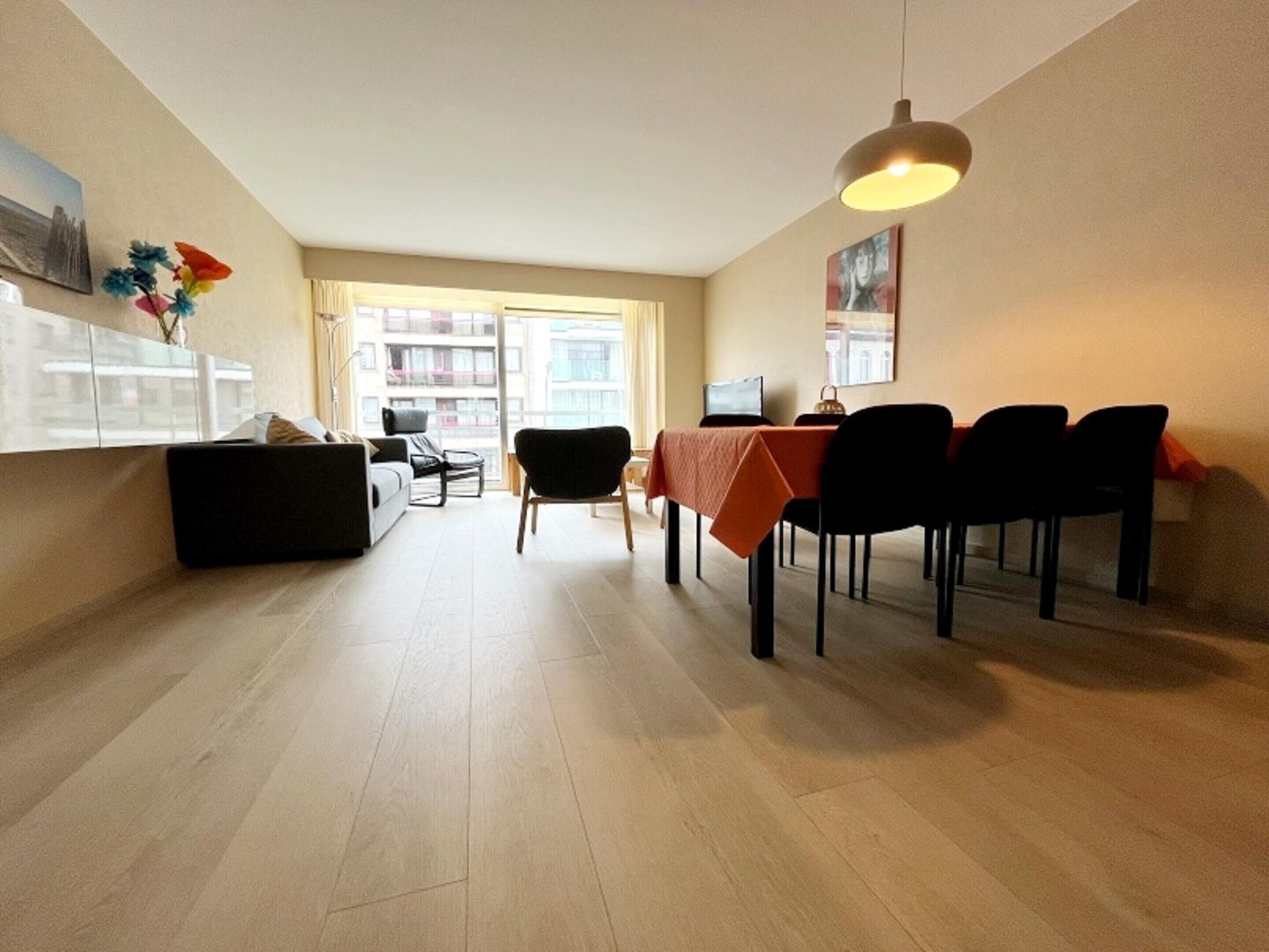 A modern living room with a dining area, large windows, and a view of the cityscape.