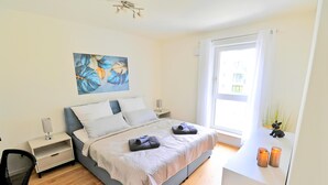 A modern bedroom with a bed, bedside tables, a desk, and a window. - RelaxRefugium / 6 pers. / Garage / 2xWorkspace (Königs Wusterhausen)