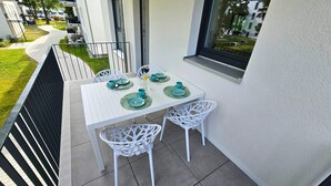 A small outdoor balcony with a white table set for two, surrounded by white chairs. - RelaxRefugium / 6 pers. / Garage / 2xWorkspace (Königs Wusterhausen)