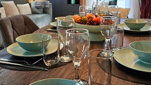 A dining table set with clear glassware and plates, a bowl of fruits and nuts, and a clock on the wall. - RelaxRefugium / 6 pers. / Garage / 2xWorkspace (Königs Wusterhausen)