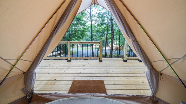 A tent with a wooden deck and a metal railing. - Firefly Ridge (Great Cacapon)