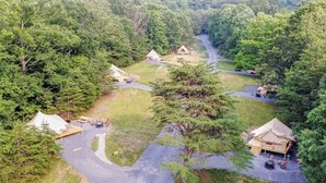 An aerial view of a campsite with multiple tents and cabins, surrounded by dense forest. - Firefly Ridge (Great Cacapon)