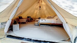 A tent with a bed, a chair, and a small table. - Firefly Ridge (Great Cacapon)