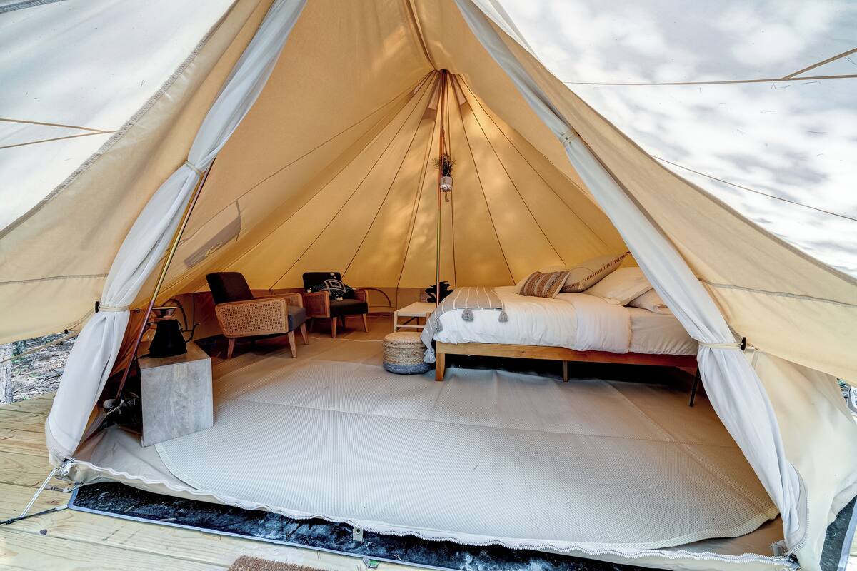 Ein Zelt mit Bett, Stuhl und kleinem Tisch.