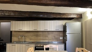 A compact kitchen with wooden cabinets, a stainless steel sink, and a built-in refrigerator.