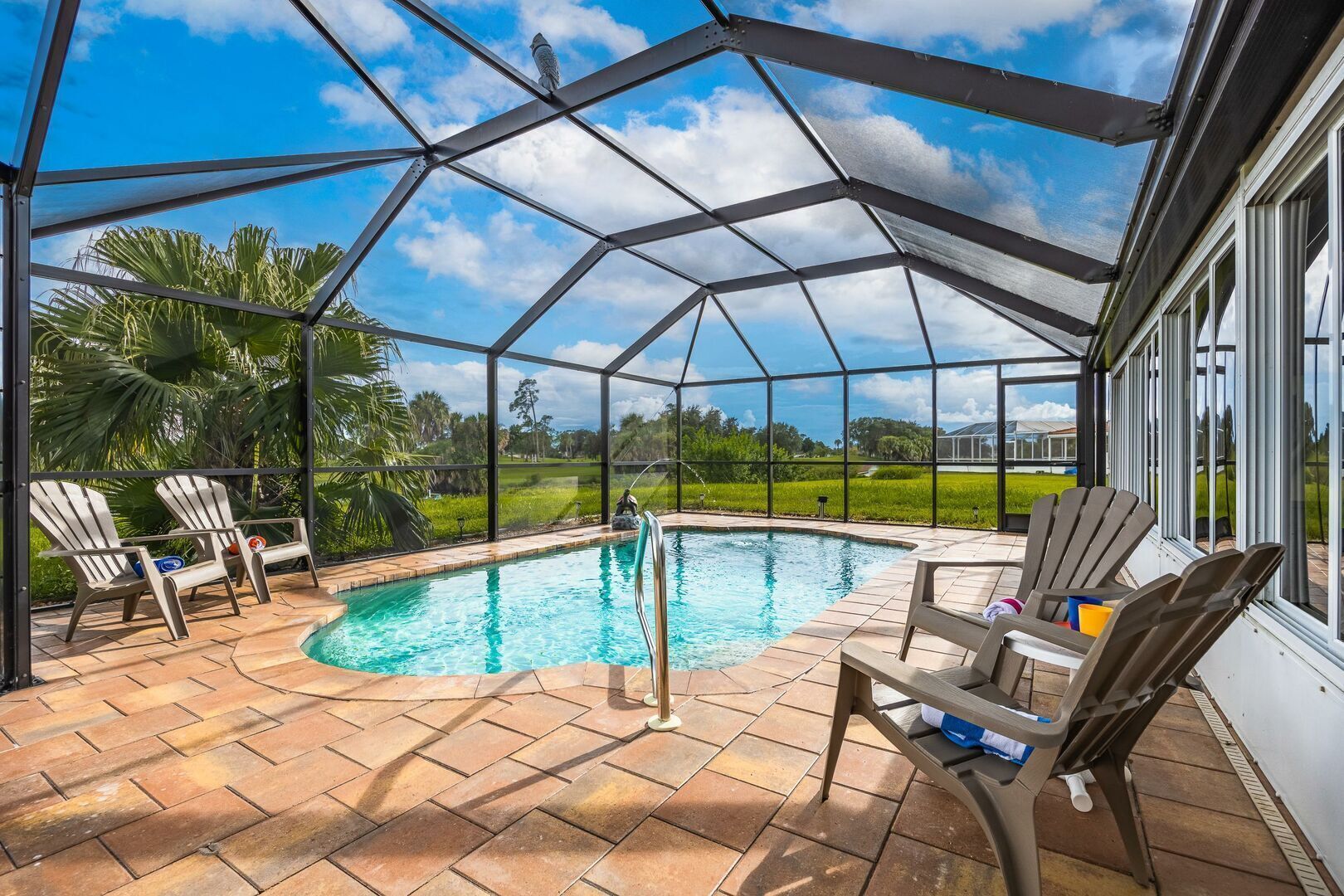 A covered outdoor swimming pool with chairs and a view of the surrounding landscape.