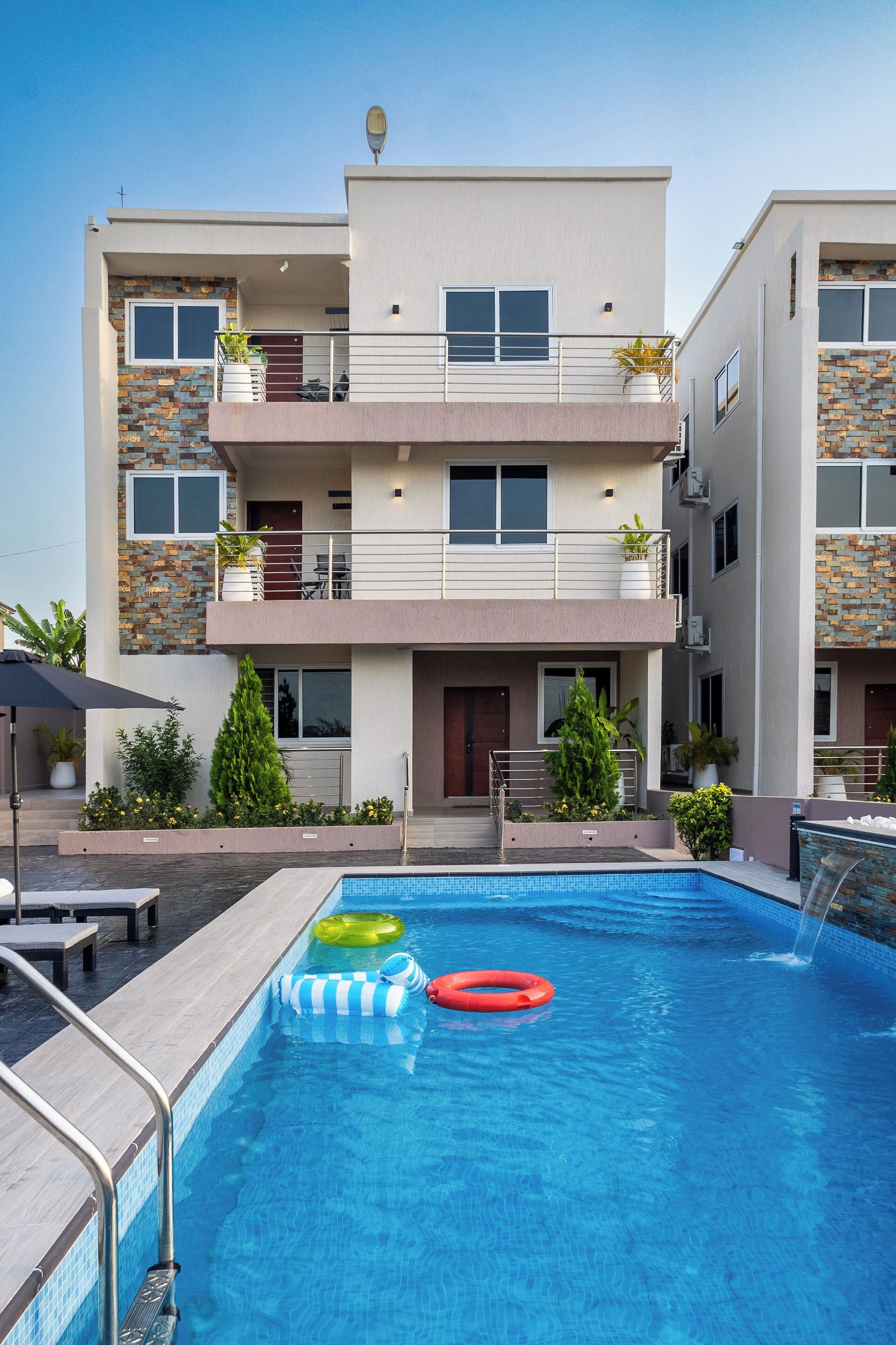 A modern hotel with a swimming pool, multiple balconies, and outdoor seating.