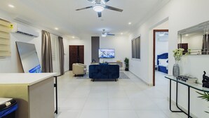 Una sala de estar moderna con un sofá, televisor y ventilador de techo.
