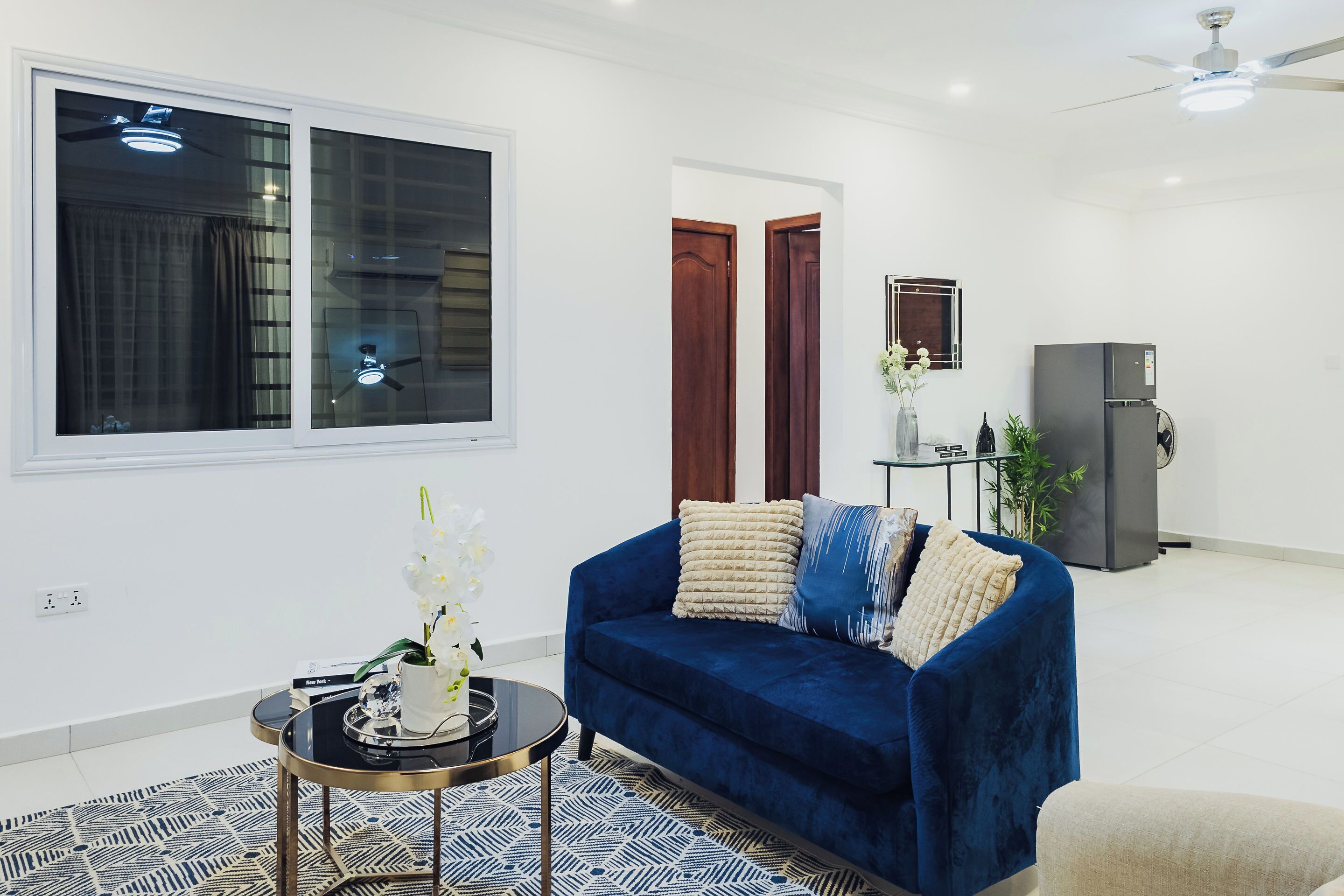 Un salon moderne avec un canapé bleu, une petite table basse ronde et un tapis à motifs.