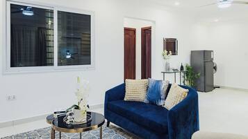 Un salon moderne avec un canapé bleu, une petite table basse ronde et un tapis à motifs.