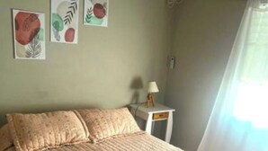 Een slaapkamer met een bed, nachtkastje en wanddecoratie.