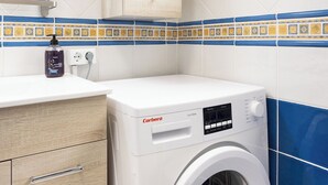 Un lave-linge compact dans une cuisine moderne, avec des meubles en bois et un dosseret de carrelage bleu.
