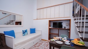 Una habitación con una cama, una mesa de comedor con productos para el desayuno, un televisor y una escalera.