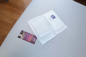 Une serviette blanche, soigneusement pliée, avec une étiquette, posée sur une surface blanche texturée.