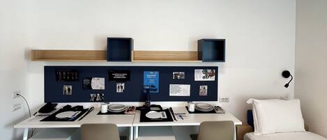 Una habitación de hotel moderna con escritorio, dos sillas, una cama y una pequeña mesa de comedor.