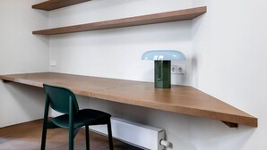 A workspace with a wooden desk, a green chair, and a wall-mounted lamp. - Barcelona Oasis With 2 Bedrooms (Barcelona)