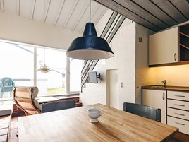 Una cocina moderna con armarios de madera, una mesa de comedor con sillas y una lámpara colgante grande.