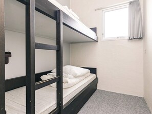 Une chambre avec un lit superposé, une fenêtre et une porte.