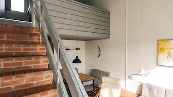 A staircase with a modern design, a dining area with a table and chairs, and a sofa.