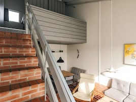 Una escalera de diseño moderno, un comedor con mesa y sillas, y un sofá.