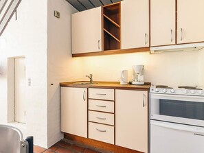 A kitchen with white cabinets, a stove, and a coffee maker. - 6 Person Holiday Home in Brovst (Brovst)