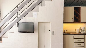 A compact kitchen with a built-in TV, a small door, and a staircase leading to another level. - 6 Person Holiday Home in Brovst (Brovst)