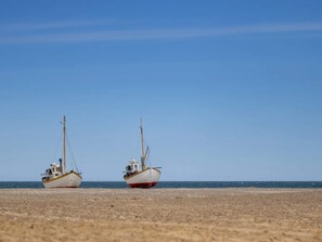 Deux bateaux sur une plage de sable, sous un ciel dégagé.