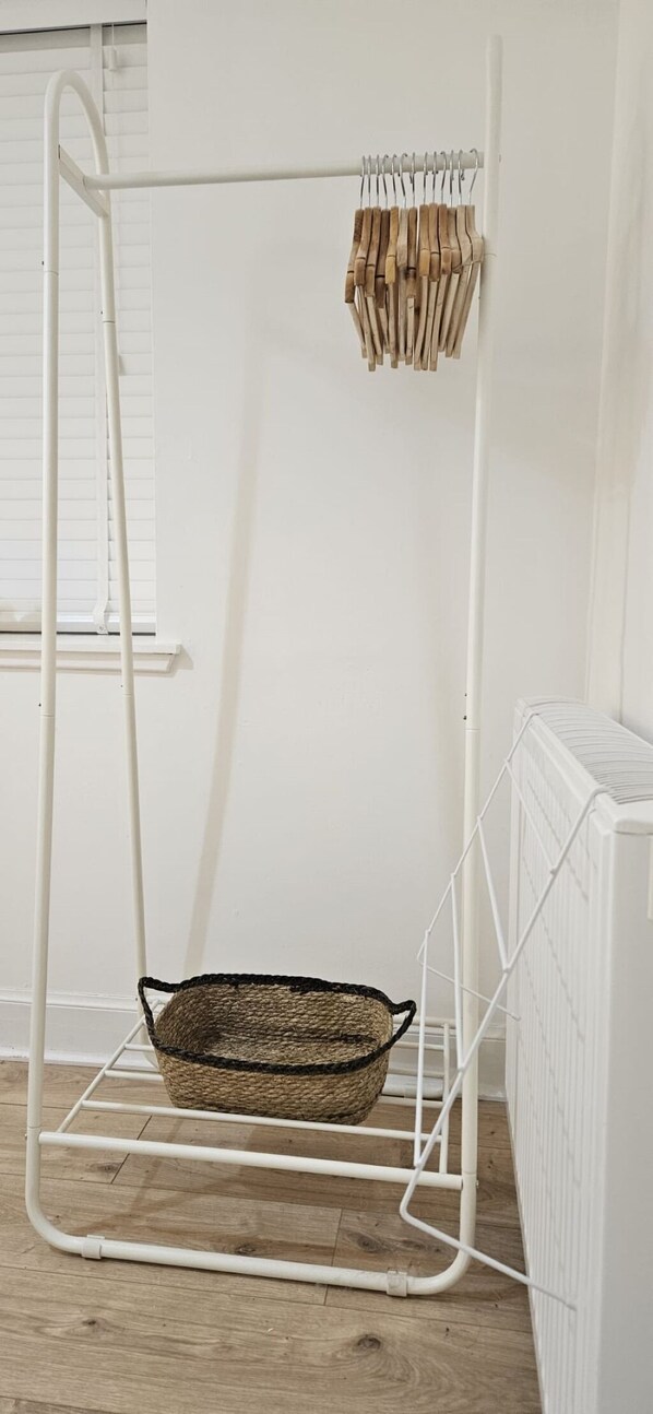 A white metal stand with a woven basket and wooden clothespins.