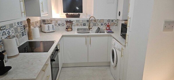 A compact kitchen with a sink, a toaster, a microwave, and a washing machine.