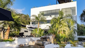 Un bâtiment moderne à l’extérieur blanc, doté de grandes fenêtres et d’un jardin sur le toit.