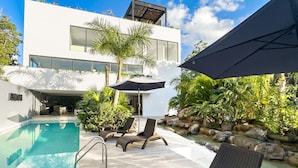 Une maison moderne dotée d’une piscine, de mobilier d’extérieur et d’un espace patio.