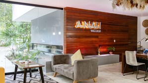 Un salon moderne avec un canapé gris, une petite table et un mur décoratif en bois sur lequel est inscrit le mot « ANALIVILLE ».
