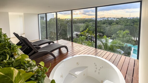 Un balcon moderne doté d’un jacuzzi, de chaises longues et offrant une vue sur un quartier résidentiel.