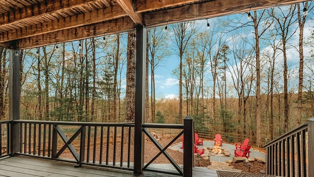 A wooden deck with a railing overlooking a forested area.