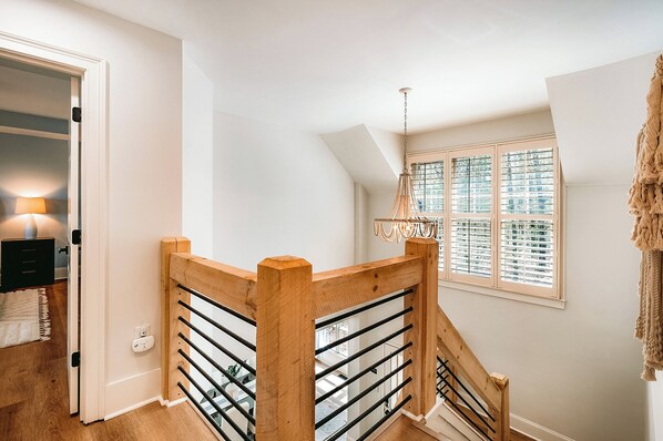 Un escalier avec des rampes en bois et un luminaire suspendu.
