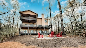 A two-story building with a balcony, surrounded by trees and a wooden fence.